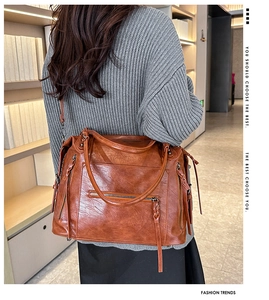 Detailed view of brown faux leather hobo bag with zipper accents and long woven pulls