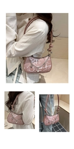 Pink crescent hobo bag with white letter patterns, metal chain, and pearl charm detail