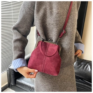 Detailed view of the burgundy suede texture and vintage metal clasp of the handbag