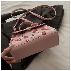 Close-up of pink cherry print handbag with adjustable strap on professional background