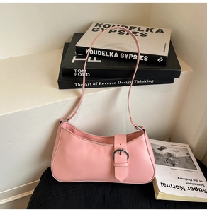 Detailed view of pink leather baguette bag with silver metal buckle on a minimalist setup