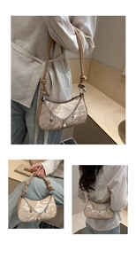 Detail of beige crescent underarm bag with pearl heart chain and knot strap design