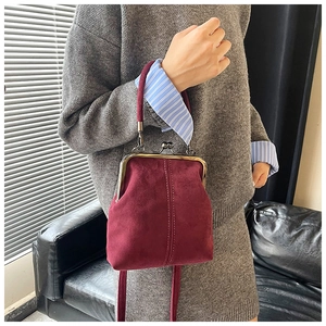 Detail view of burgundy suede kiss-lock bag with vintage metal clasp and fine stitching