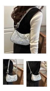 Detail of silver-grey shoulder bag with abstract patterns and decorative pearl chain
