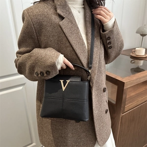Women's black pebbled leather handbag with gold V-logo and crossbody strap for office style