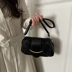 Borsa a spalla chic in jacquard nero con fibbia dorata abbinata a un trench coat beige