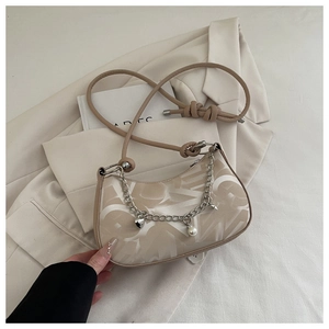 Close-up of beige crescent shoulder bag with metal chain, heart pearl charm and logo texture