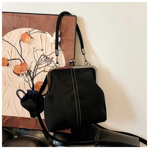 Detail of a vintage black kiss-lock bag with white stitching on high-quality matte leather