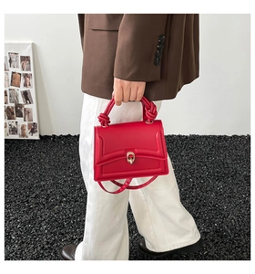 Detail of red leather handbag with unique knotted handle and golden buckle clasp