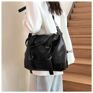 Close-up of a large black soft leather tote bag with silver hardware on a model