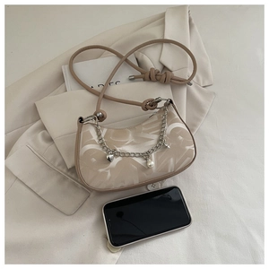 Chic beige half-moon shoulder bag with chain heart pendant shown next to a smartphone