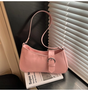 Detailed view of pink leather baguette bag with silver metal buckle on a design book