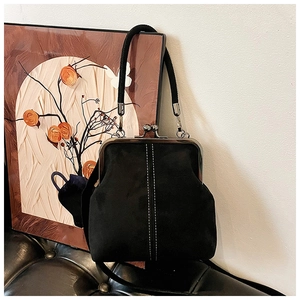 Close-up of black vintage frame bag with white stitching and silver metal clasp detail