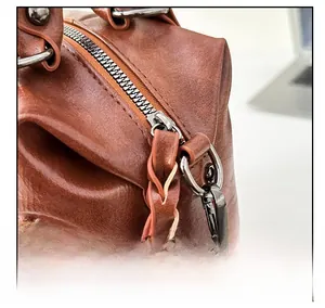 Detail of smooth metal zipper and woven leather decorative strap on brown bag