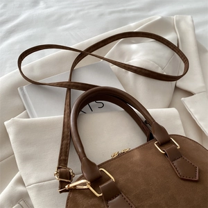 Close-up of dark coffee frosted leather shell bag with gold hardware and shoulder strap