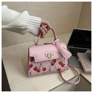 Detail of pink cherry print shoulder bag with gold twist lock and adjustable strap