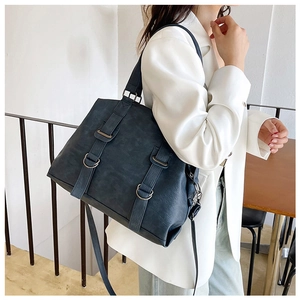 Detail view of a vintage dark blue leather tote bag with stylish metal rings and straps