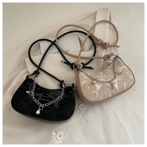Close-up of semi-circle underarm bags with artistic letter patterns and pearl chain details