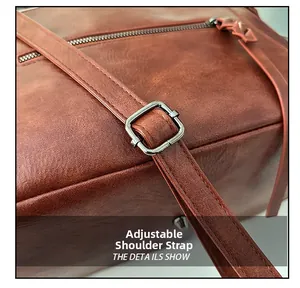 Detail view of adjustable brown leather shoulder strap with metallic buckle and stitching