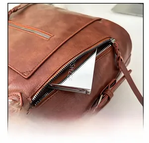 Detail view of the brown leather tote bag showing a side zipper pocket with a small mirror