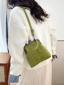 Detail of sage green suede crossbody bag with vintage kiss-lock and circular top handle