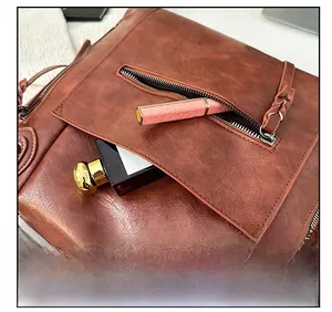Detail of vintage brown leather bag showing external zipper pocket with woven puller