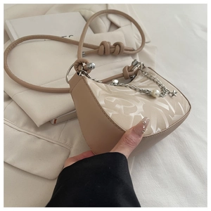 Detail of beige crescent shoulder bag with jacquard texture and silver star pearl chain