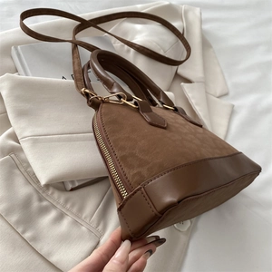 Detail of a brown shell bag with suede and PU leather contrast on a white blazer