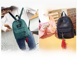 Close-up of corduroy backpack texture with logo label and red fringe tassel detail