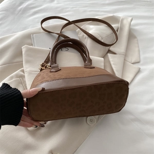 Detail of leopard print faux fur texture and brown leather trim on a Boston bag