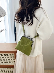 Detail of avocado green vintage frame bag with metal clasp shown in a lifestyle setting
