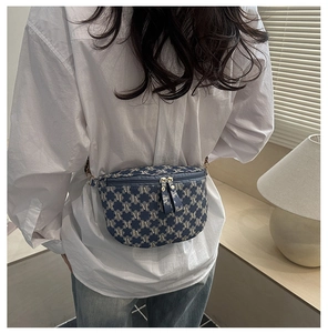 Detail of blue jacquard waist bag with M-pattern and double zipper on female model