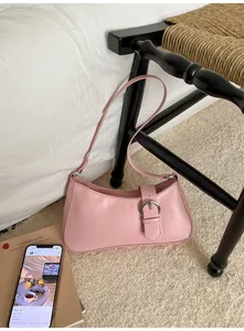 Detailed shot of pink baguette bag with silver buckle on a chair in a cozy setting