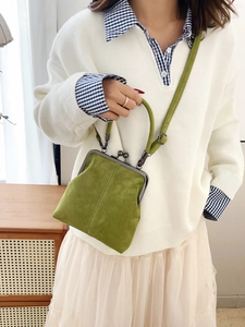Crossbody shot of a vintage grass green suede frame bag with a metal clasp closure