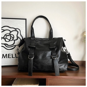 Detail of black textured leather tote with long decorative straps and silver D-rings