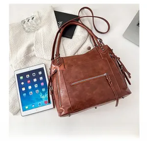 Detail view of brown leather bag with metal zippers and anti-wear bottom studs