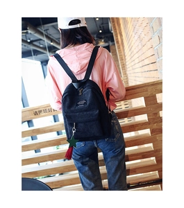 Detail of black corduroy backpack with star charm and red tassel decoration