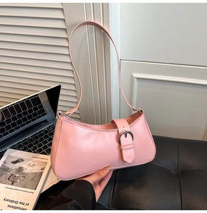 Detail of pink PU leather baguette bag with silver buckle on a laptop background