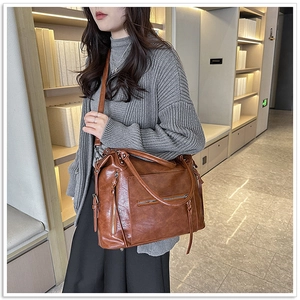 Brown leather tote bag detail with dual zippers, long tassels and textured finish