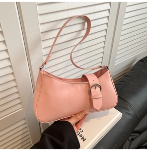 Close-up of light pink baguette bag with large silver metal buckle and faux leather texture