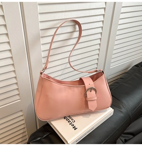 Detailed view of a pink baguette bag with silver buckle on minimalist art books