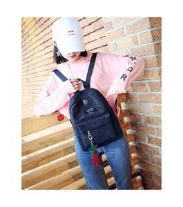 Close-up of black corduroy mini backpack with green star charm and red tassel detail