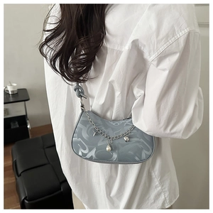 Detail of light blue hobo bag with letter patterns, metal chain and heart charms