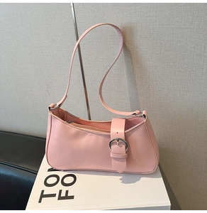 Detailed shot of pink baguette bag with silver buckle and shoulder strap on a white box