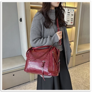 Detail shot of a dark red oversized leather tote with tassel zippers and metal rivets