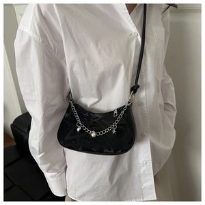 Detail of black crescent shoulder bag with silver chain, pearl charms and star pendants