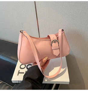 Detail view of pink leather underarm bag featuring a metallic buckle and semi-circular shape