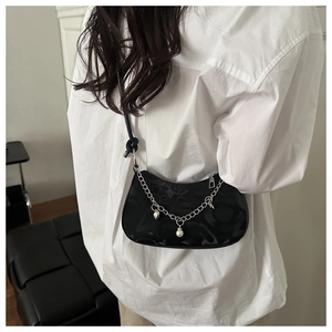 Detail of black crescent shoulder bag with silver chain, pearl charms and embossed texture