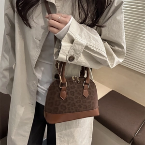 Brown leopard print shell bag with leather trim and gold hardware on model