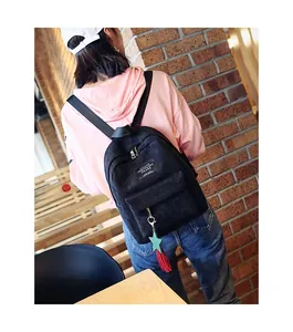 Rear view of a black corduroy mini backpack with colorful tassel pendant on a model